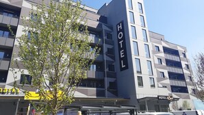 Un moderno edificio de hotel con un llamativo letrero que dice 'HOTEL' en la fachada, varios balcones y un cielo despejado.