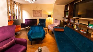 Una sala de estar moderna con un sofá azul, sillones morados y una estantería.