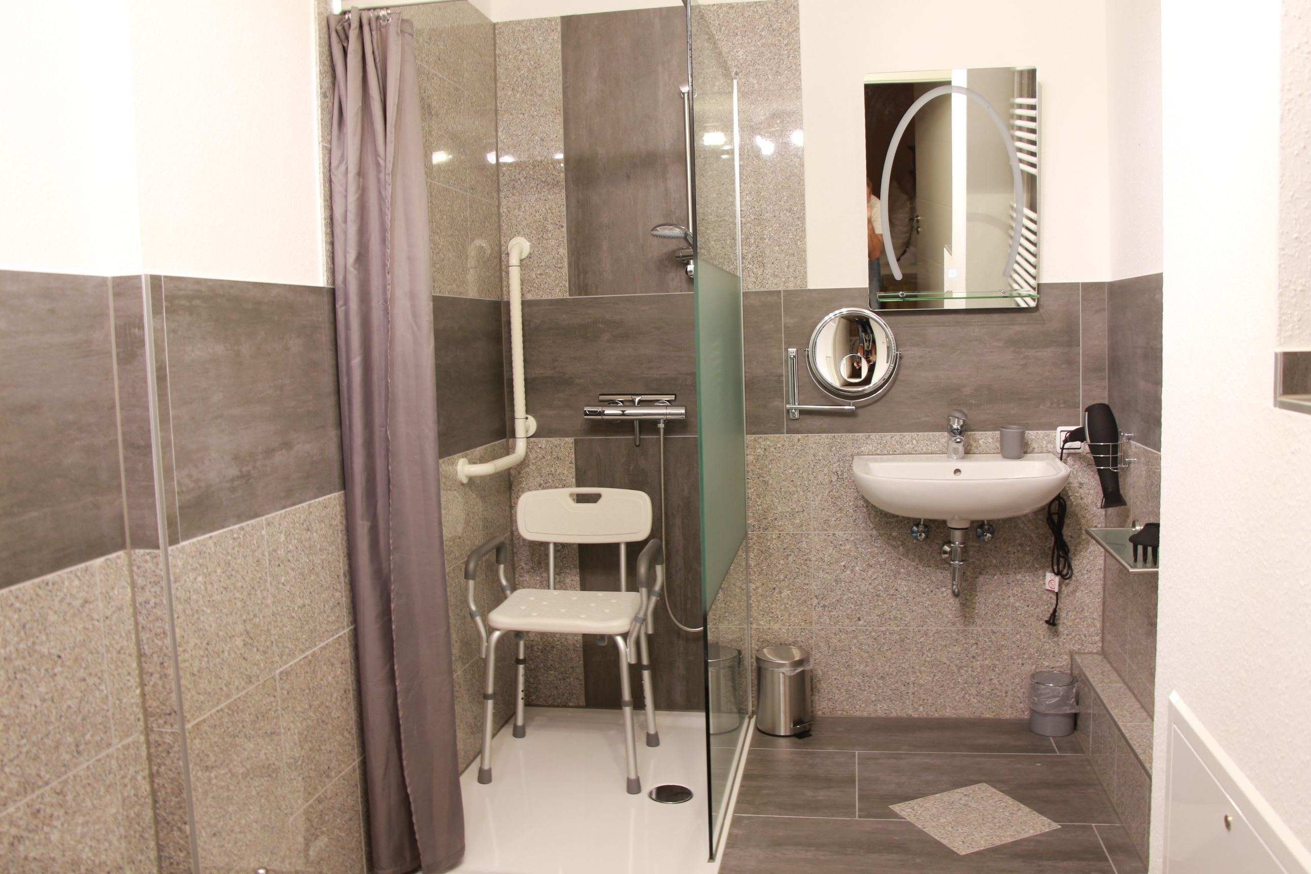 Ein modernes Badezimmer mit Dusche, Toilette, Waschbecken und einer Duschkabine aus Glas.