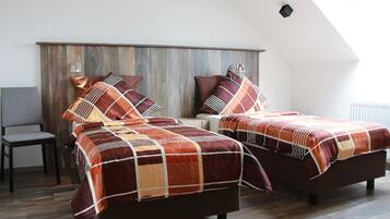 A bedroom with two beds, a wooden headboard, a chair, and a window.