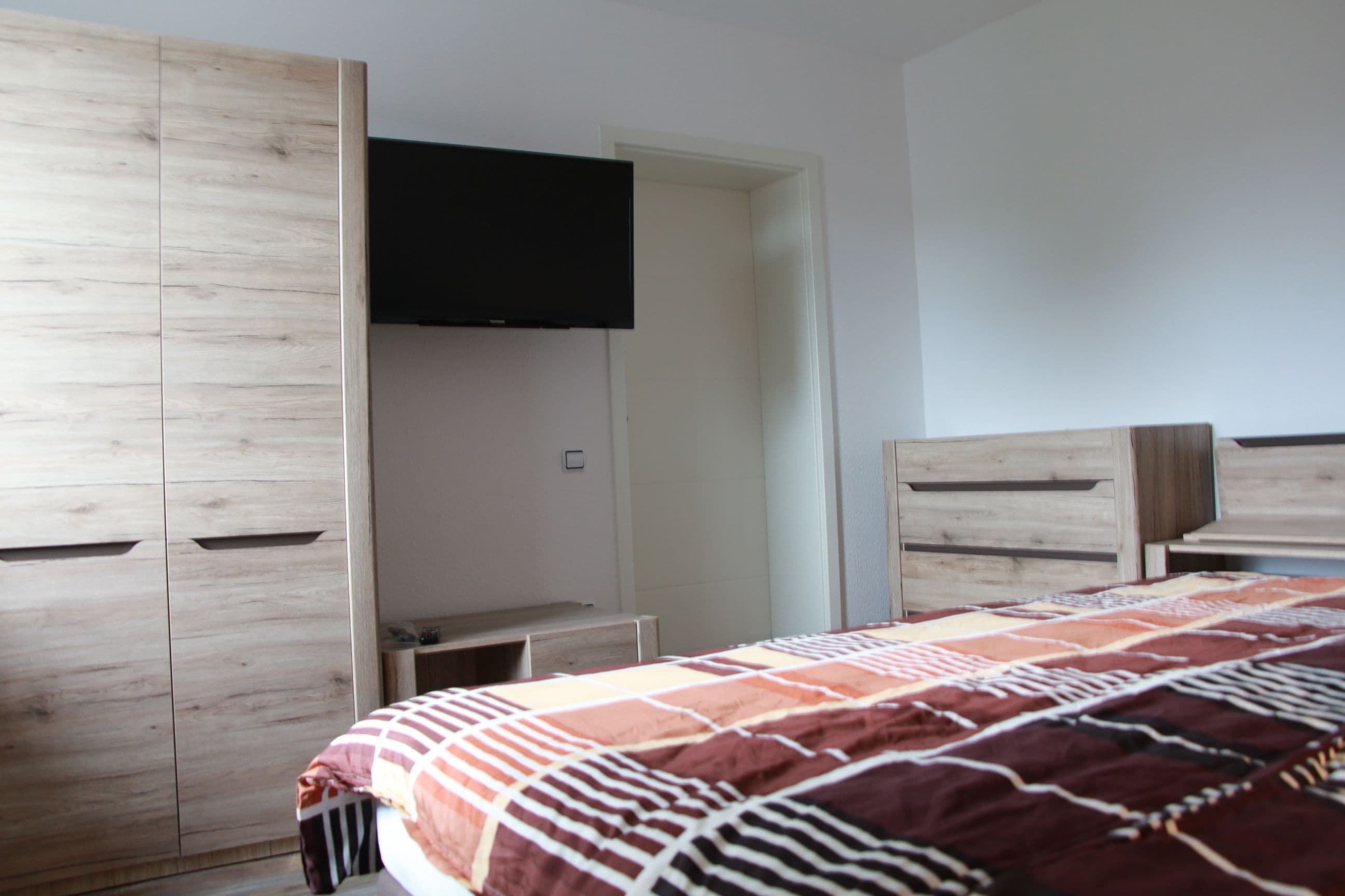 Ein Schlafzimmer mit Bett, Kleiderschrank und Fernseher.