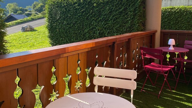 Un balcon avec vue sur une montagne, une clôture en bois et une table avec des chaises.
