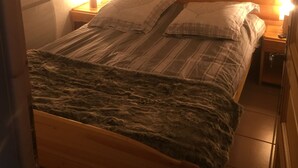 Un lit en bois avec une tête de lit, deux tables de chevet avec des lampes et une couverture.
