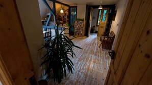 A wooden interior with a staircase, a large potted plant, and a bookshelf.