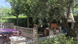 An outdoor patio with a tiled table and chairs, surrounded by brick walls and greenery. - Exclusive Vila with private pool, wifi and air condition (Cambrils)