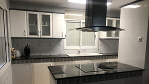 A modern kitchen with white cabinets, a black countertop, and a glass island. - Exclusive Vila with private pool, wifi and air condition (Cambrils)