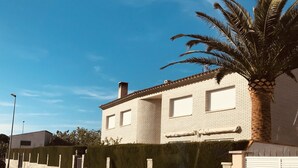A two-story building with a tiled roof, a stone wall, and a palm tree in front. - Exclusive Vila with private pool, wifi and air condition (Cambrils)