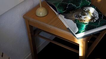 A wooden table with a lamp, a glass, and a book with a green cover.