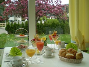 Une table mise pour le petit-déjeuner, avec une variété de viennoiseries, de fruits et de boissons, préparée pour deux personnes.