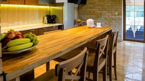A modern kitchen with wooden cabinets, a stone wall, and a wooden dining table with chairs.