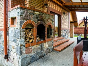 Een stenen gebouw met twee bakovens, trappen naar een overdekt terras en buitenzitplaatsen.