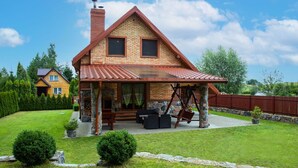 A two-story house with a brick exterior, a tiled roof, and a covered porch with outdoor furniture.