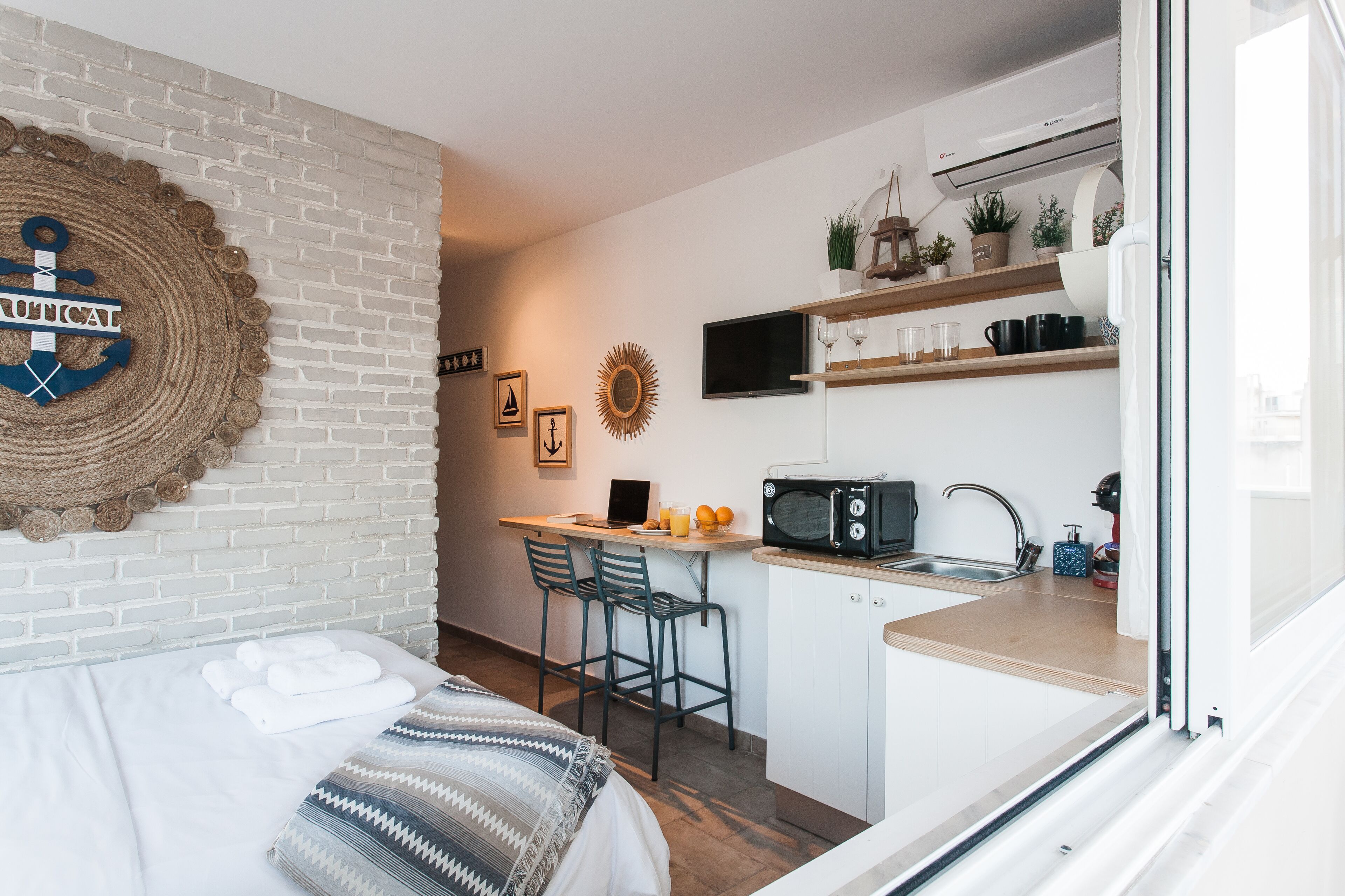 A compact hotel room with a bed, a small kitchenette, a dining area, and a bathroom.