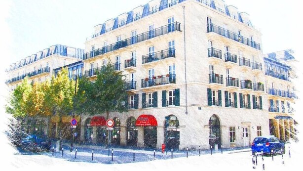 Un immeuble à plusieurs étages, doté de balcons, de fenêtres en arc de cercle et d’une rangée de boutiques au rez-de-chaussée.
