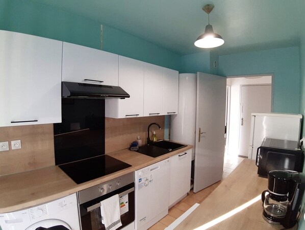 A compact kitchen with a stove, oven, dishwasher, and a coffee maker.
