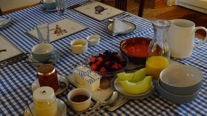 Ein Frühstückstisch mit verschiedenen Speisen, darunter Obst, eine Karaffe und eine Tasse.
