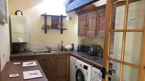 Eine kompakte Küche mit Waschmaschine, Mikrowelle und einem Siemens-Kühlschrank.