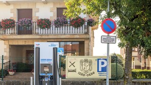 Un área de estacionamiento con estaciones de carga para vehículos eléctricos, un letrero de estacionamiento privado y un letrero de prohibido estacionar.