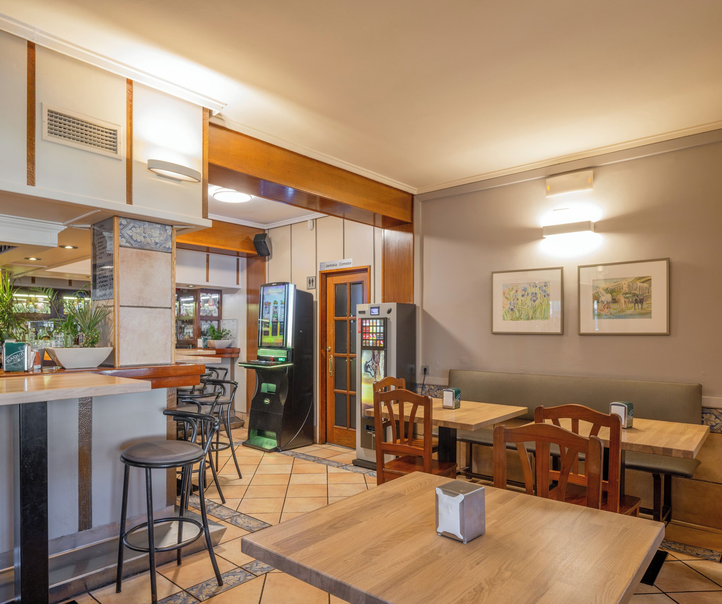 A restaurant with wooden furniture, a bar area, and a vending machine.