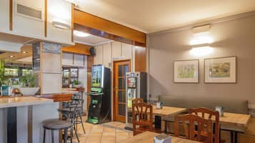 A restaurant with wooden furniture, a bar area, and a vending machine.