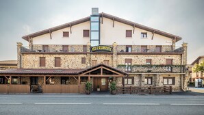 Un edificio de piedra de dos pisos con un letrero que dice "RESTAURANTE" y un área de estar al aire libre cubierta.
