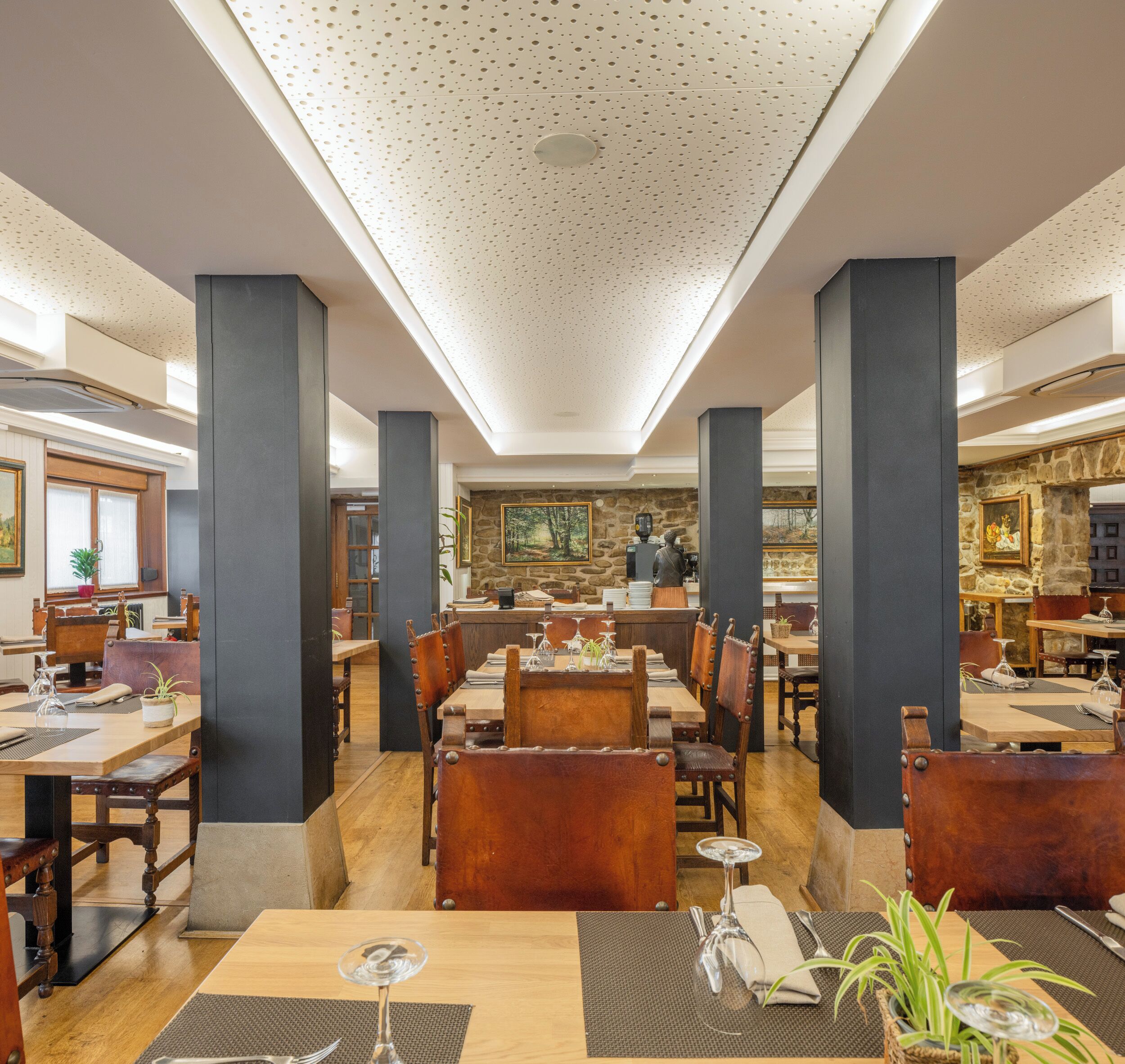 A spacious restaurant with high ceilings, wooden tables, and leather chairs.