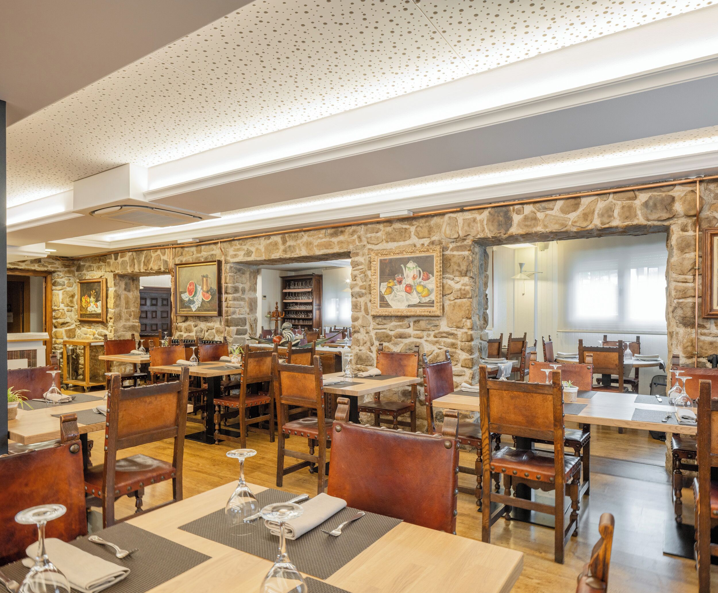 A restaurant with stone walls, wooden tables, and chairs.