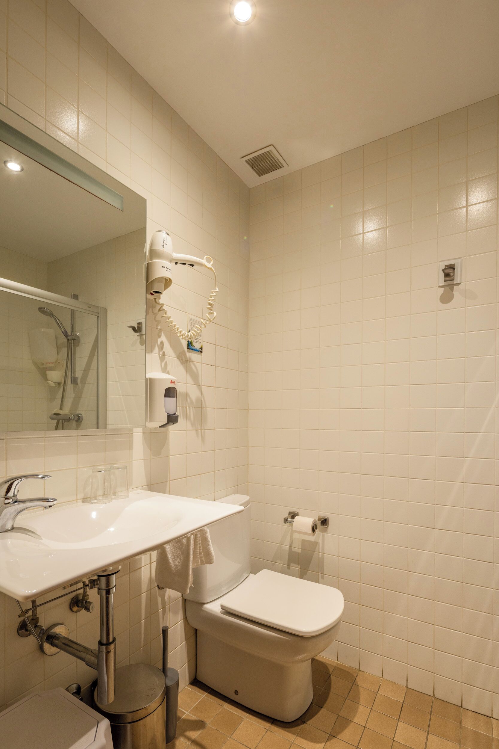 Un bagno con lavandino, water e specchio bianchi.