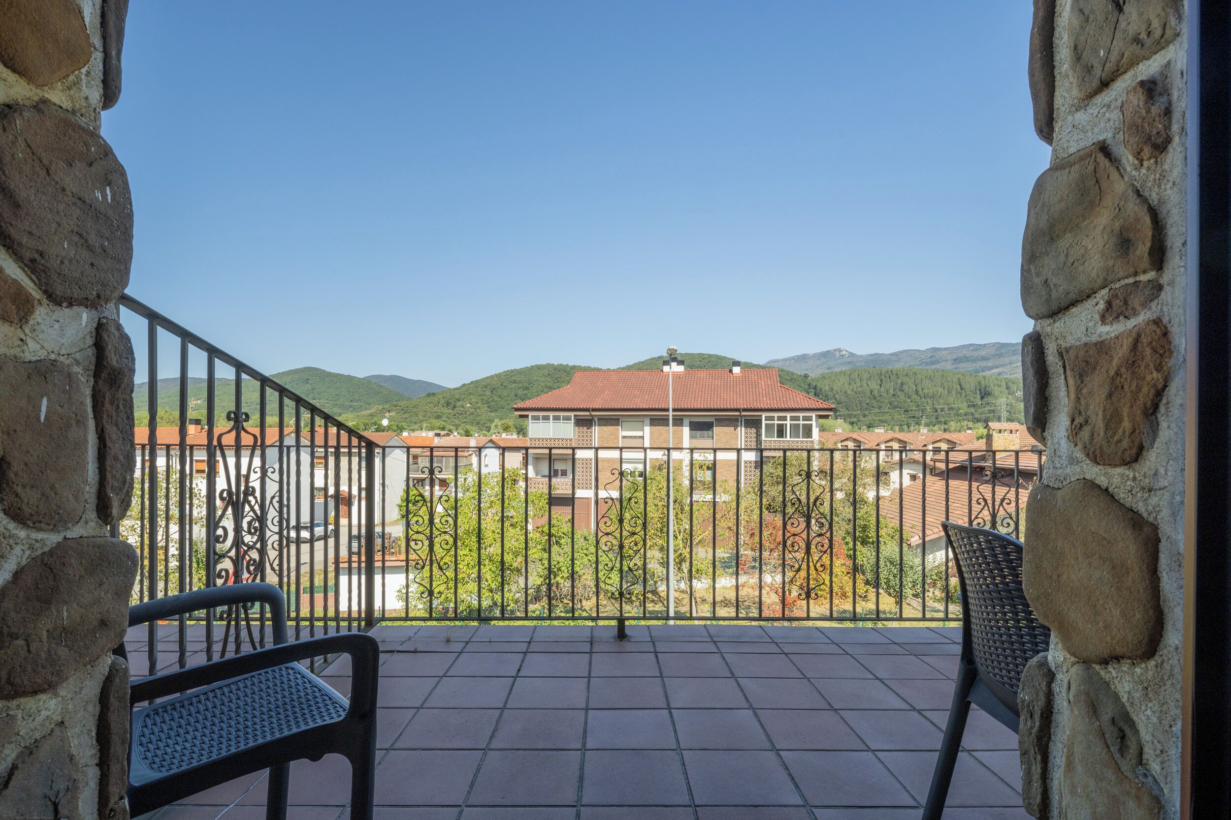 Ein Balkon mit Blick auf ein Gebäude und Hügel.