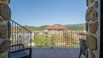 Ein Balkon mit Blick auf ein Gebäude und Hügel.