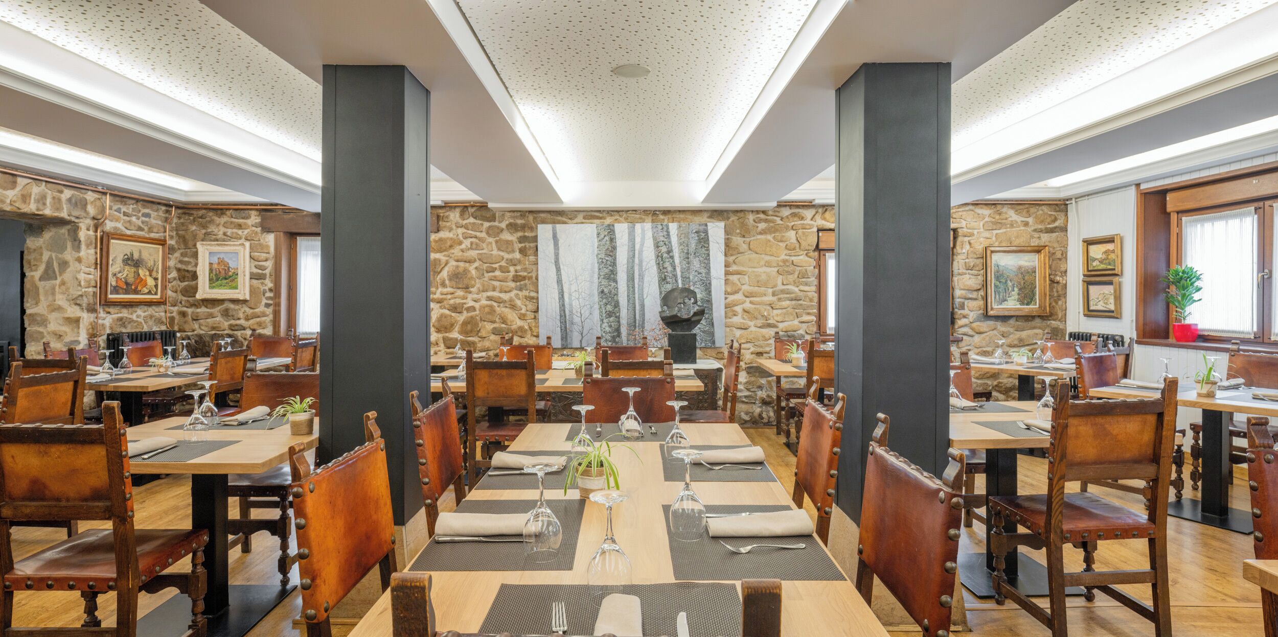 A restaurant with stone walls, wooden tables, and chairs.