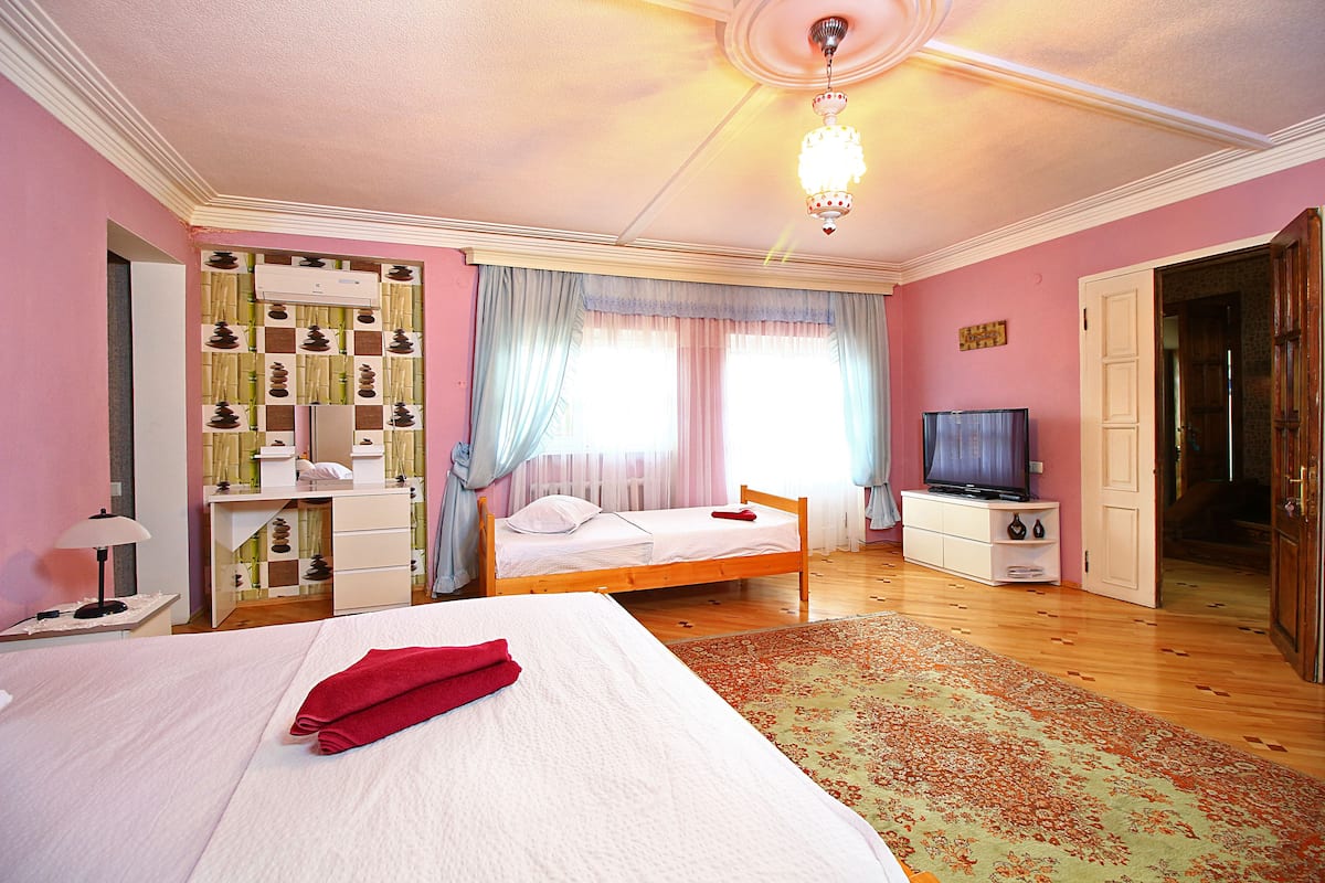 A bedroom with a bed, a TV, a dresser, and a wardrobe.