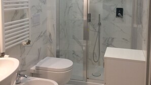 A modern bathroom with a glass-enclosed shower, a white sink, a bidet, and a toilet. - SOGGIORNISORRENTO (Sorrento)