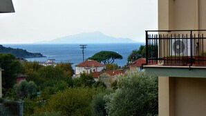 A coastal view with a mountain in the background, a tree, and buildings with red roofs. - SOGGIORNISORRENTO (Sorrento)