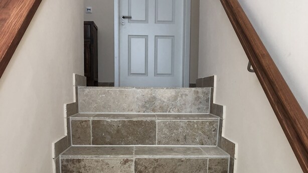 Un escalier en pierre mène à une porte blanche.