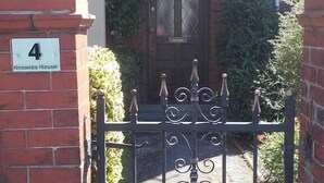 A gated entrance to a house with a brick facade, a number plaque, and a decorative iron gate. - EsJays at Knowles House (Lytham St. Anne's)