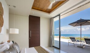 A bedroom with a large bed, a wooden ceiling, a sliding glass door leading to a balcony with a view of the ocean and outdoor seating. - Villa Natha (Koh Samui)