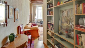 Una stanza accogliente con soffitto in legno, una libreria piena di libri, un vaso verde e un quadro appeso al muro.