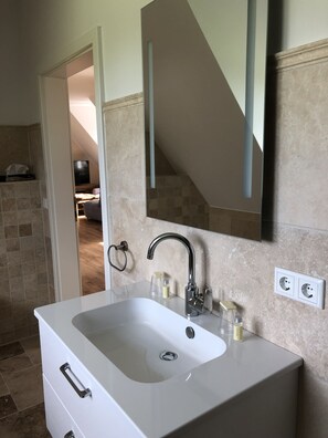 A bathroom with a white sink, a mirror, and a towel ring. - Ferienwohnung Herbstprinz (Stade)