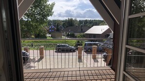 A balcony with a view of a parking area and buildings in the background. - Ferienwohnung Herbstprinz (Stade)