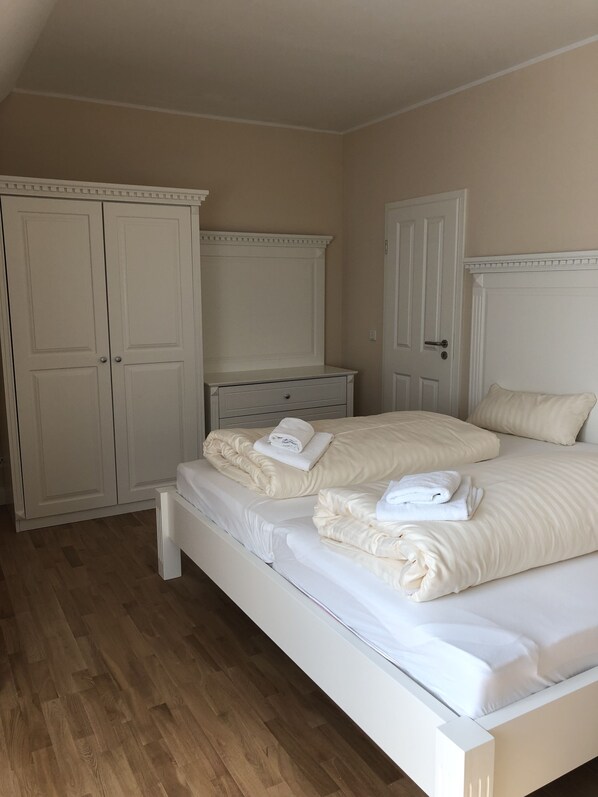 A bedroom with a large bed, two nightstands, a wardrobe, and a door. - Ferienwohnung Herbstprinz (Stade)
