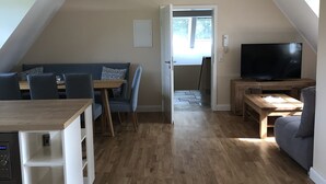 A spacious living area with a dining table, sofa, and TV. - Ferienwohnung Herbstprinz (Stade)
