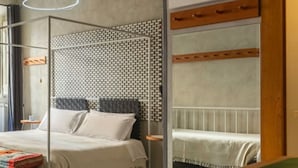 Ein modernes Schlafzimmer mit einem Himmelbett, einem gemusterten Kopfteil und Blick auf eine weiße Heizung.