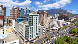 A cityscape with modern buildings, a busy street, and a mountain in the background. - Pristine Apartment in the Heart of Cape Town (Cape Town)