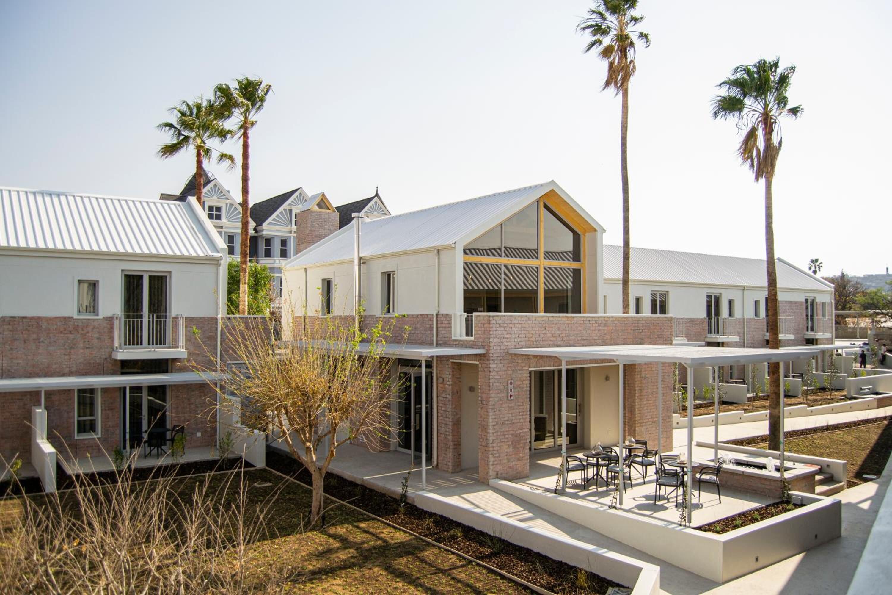 A modern multi-story building with a flat roof, large windows, and a covered outdoor seating area.