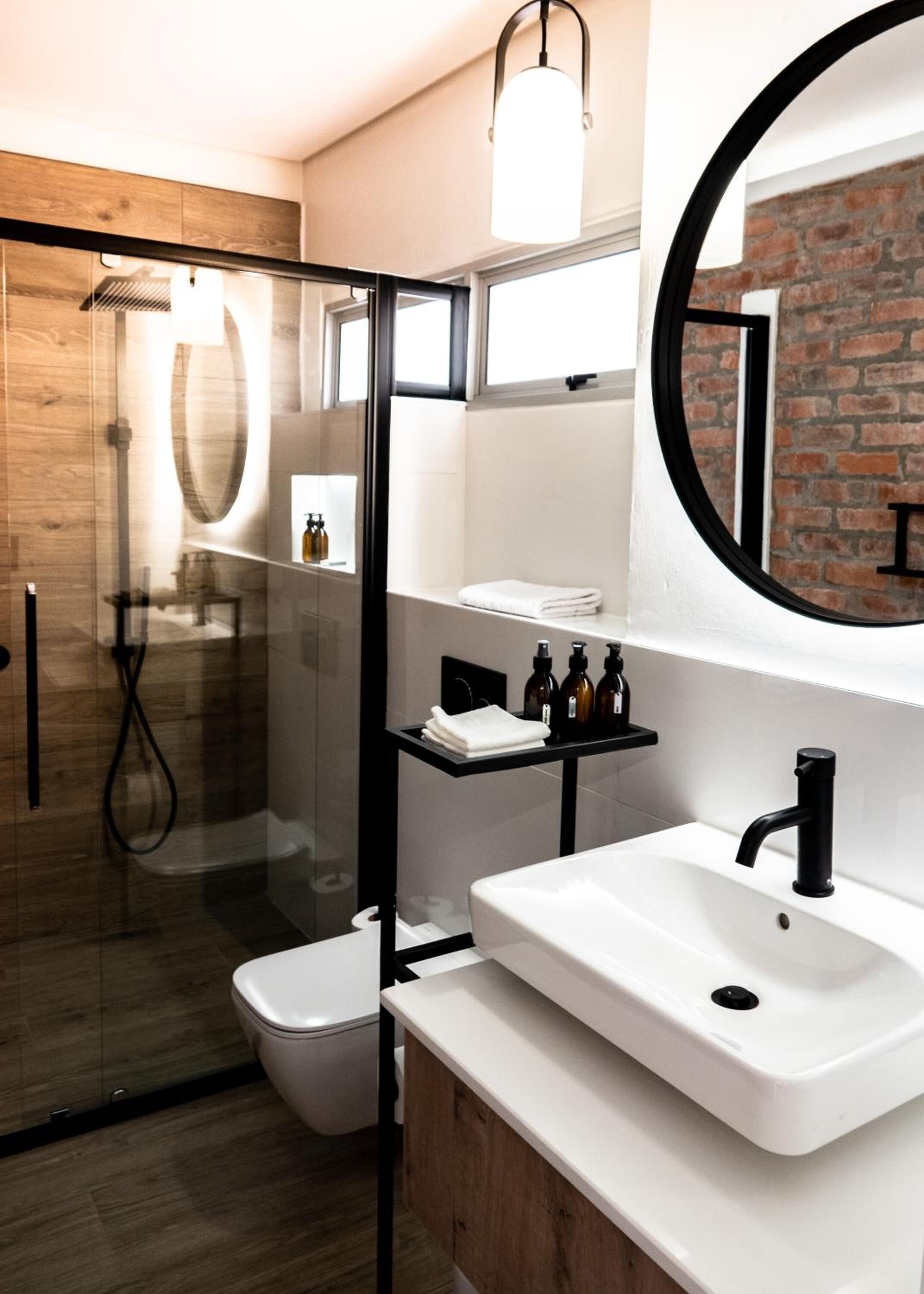 Un baño moderno con cabina de ducha de vidrio, un lavabo blanco y un espejo grande.