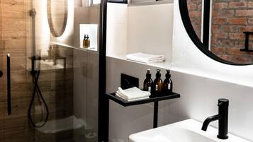 Un baño moderno con cabina de ducha de vidrio, un lavabo blanco y un espejo grande.