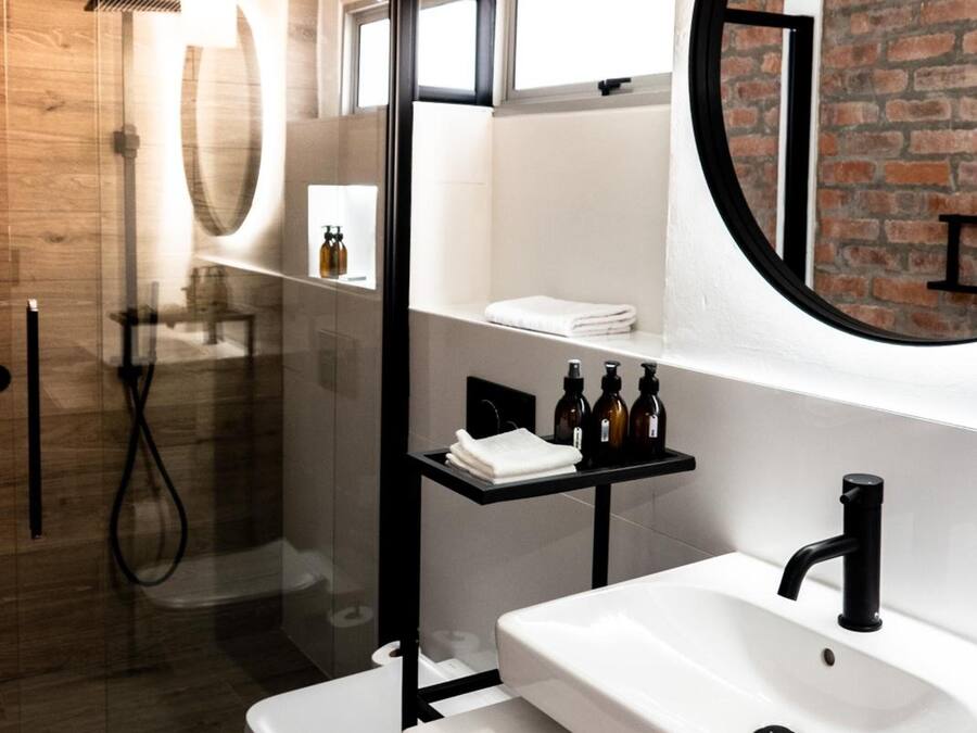 Un baño moderno con cabina de ducha de vidrio, un lavabo blanco y un espejo grande.