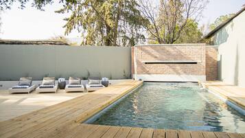 Una piscina al aire libre, sillones reclinables de piscina