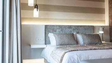 A modern bedroom with a large bed, bedside tables, and hanging pendant lights.